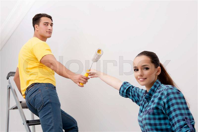 Young couple painting wall at home, stock photo