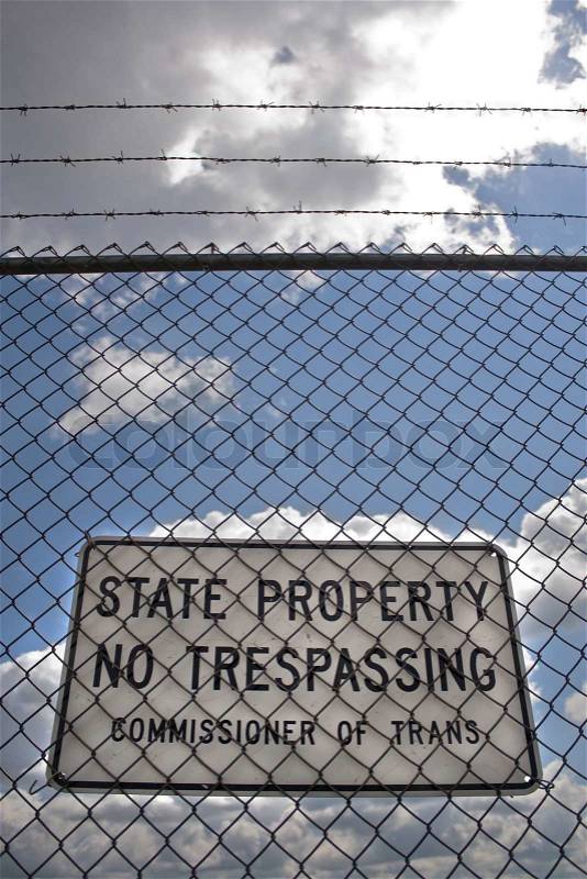 A no trespassing sign that reads STATE PROPERTY NO TRESPASSING outside an airport, stock photo