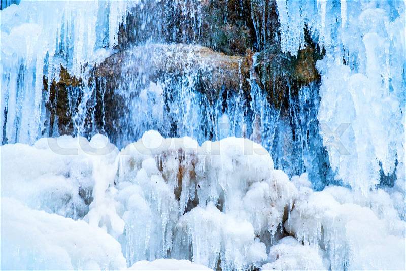 Frozen waterfall of blue icicles on the rock, stock photo
