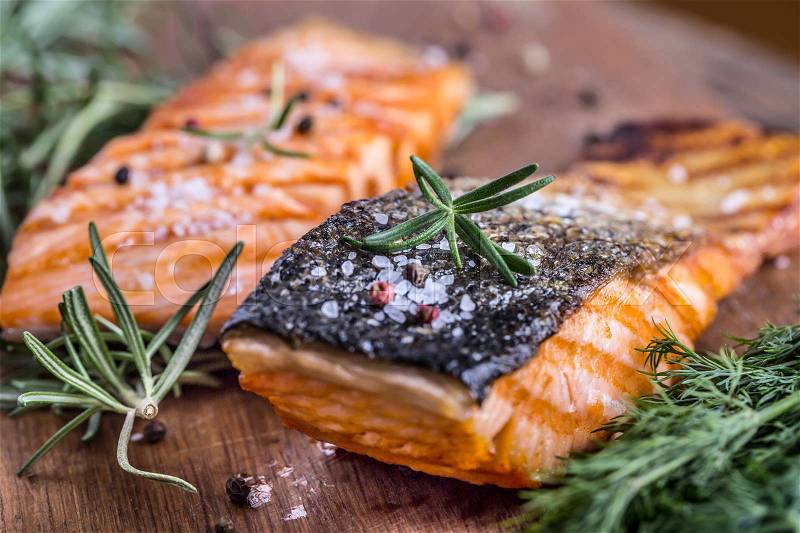 Salmon fillets. Grilled salmon, sesame seeds herb decoration on vintage pan or black slate board. fish roasted on an old wooden table.Studio shot, stock photo