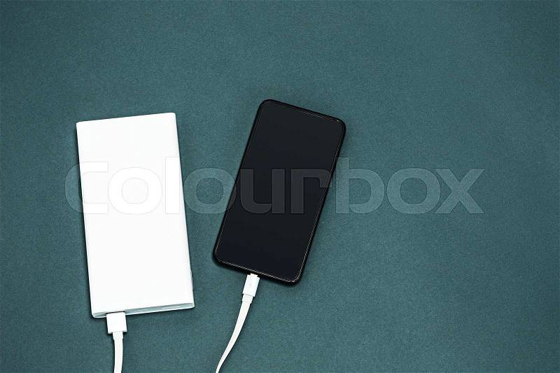 Power bank and mobile phone on gray desk, stock photo