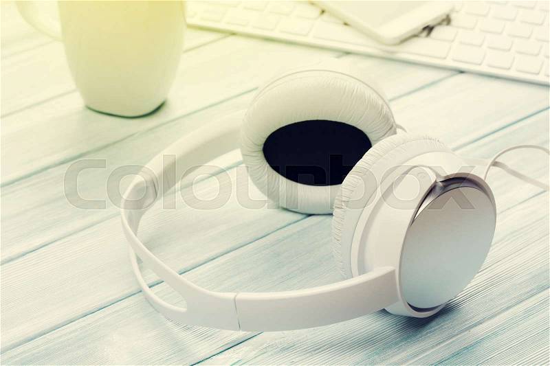 Headphones, phone and pc on wooden desk table. Music concept. Sunny toned, stock photo