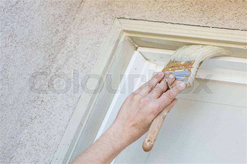 Professional Painter Cutting In With A Brush to Paint Garage Door Frame, stock photo