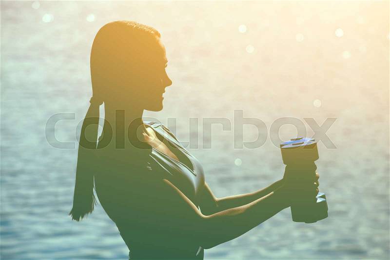 Beautiful athlete involved in sports on the street conducts training with dumbbells in his hands. The concept of a healthy lifestyle and sports culture, stock photo