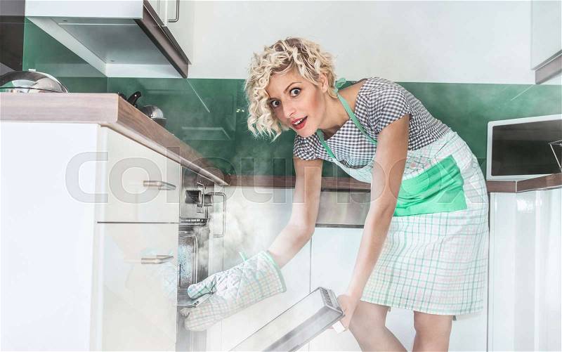 Funny woman cook frying or roasting something in a oven. Smoke, vapor around in the kitchen or home , stock photo