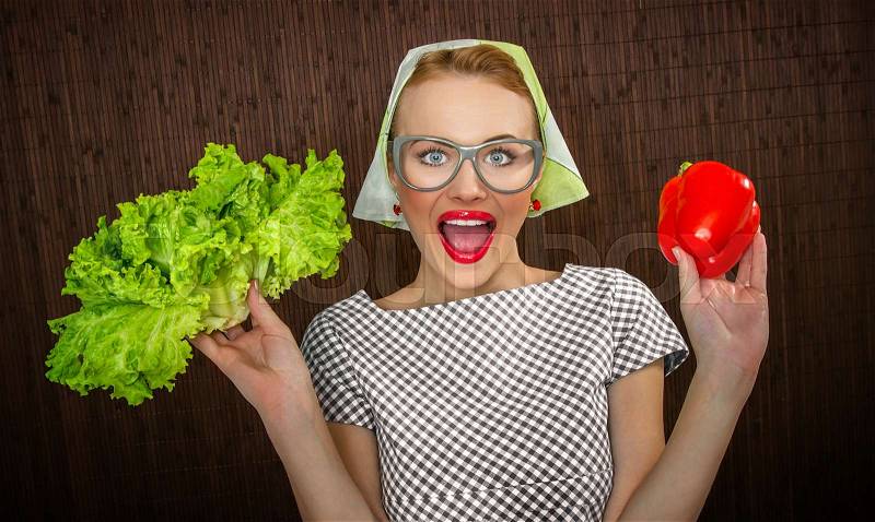 Funny woman cook holding salad and sweet pepper, close up of a housewife, stock photo