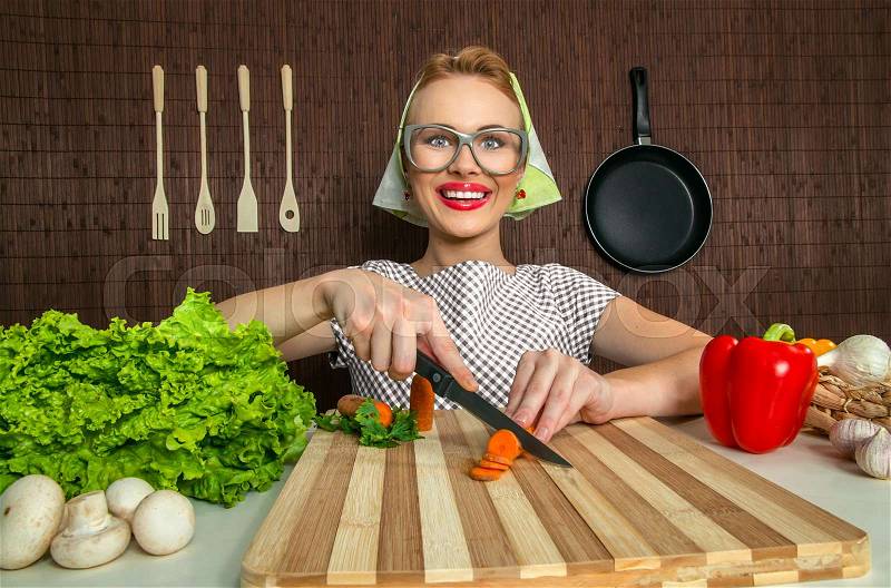 Happy funny woman cook working in the kitchen cutting carrot, stock photo