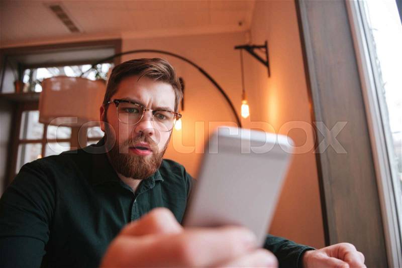 Amazed schoked man reading message or recieving photo image in coffee shop, stock photo