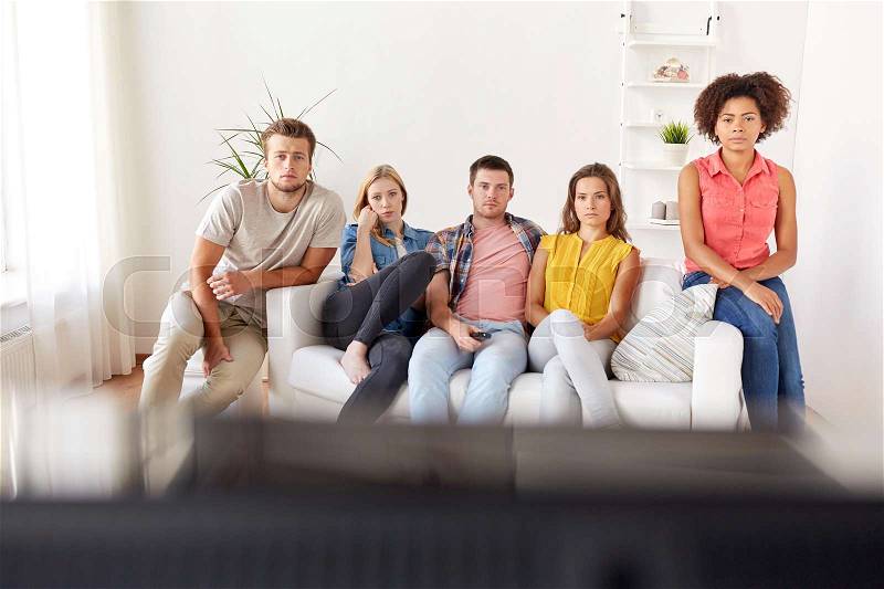 Friendship, people, mass media and television concept - sad friends watching tv at home, stock photo