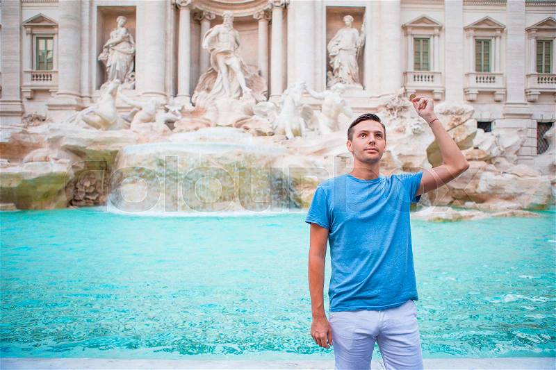 Happy man tourist trowing coins at Trevi Fountain, Rome, Italy for good luck. Caucasian guy making a wish to come back, stock photo