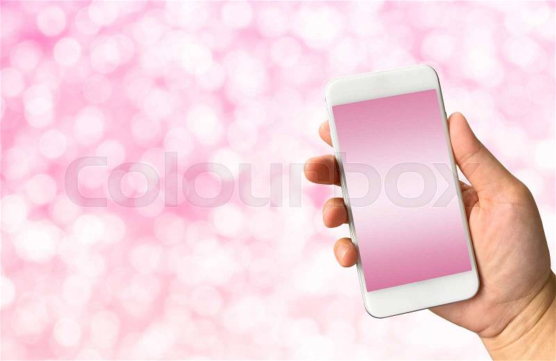 Hand holding smart phone on white pink bokeh background with copy space, stock photo