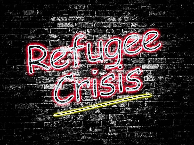 Refugee Crisis sign on old black vintage brick wall background, stock photo