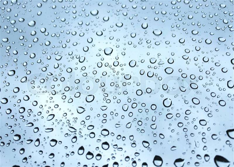 Rain drops on glass window blue sky background, stock photo