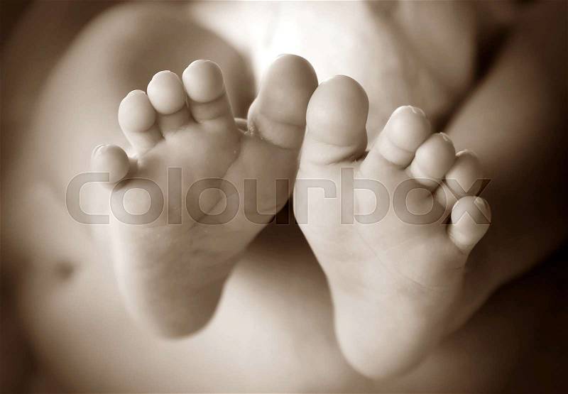 Photo of newborn baby feet in soft focus - sepia, stock photo