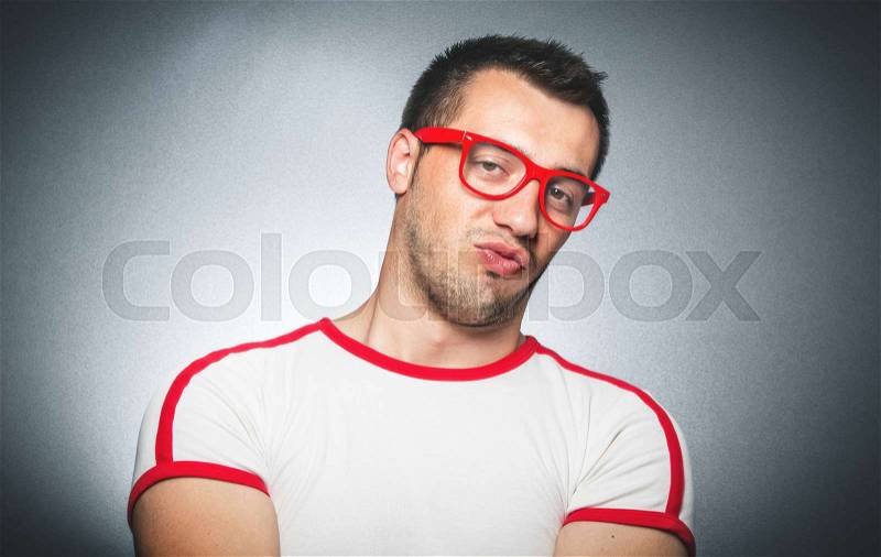 Funny young man with pursed lips laughing at trendy facebook girl make a joke over gray dark background, stock photo