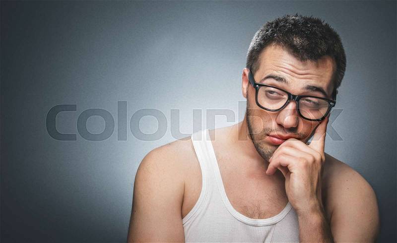 Lazy man against gray background. Close up of a tired guy, stock photo