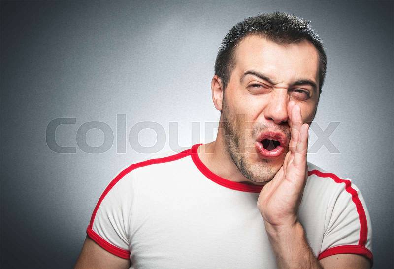 Mad funny man hands to open mouth yelling - shouting over dark gray background, studio shot, stock photo