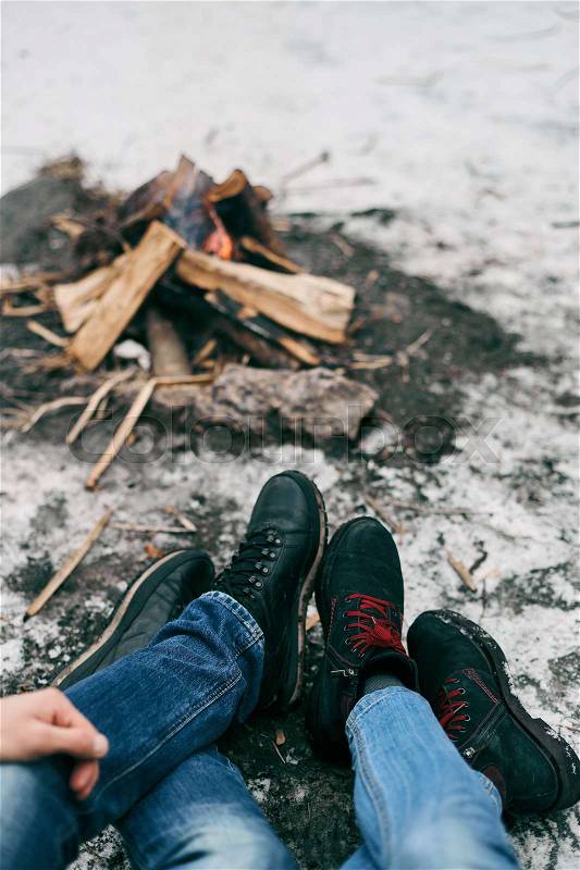 Guy and girl warm feet near a fire. Cold winter on the street, stock photo