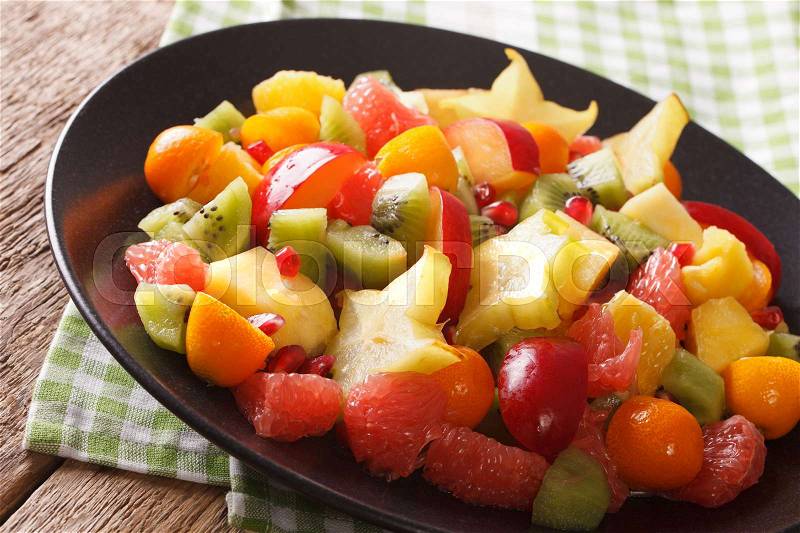 Exotic Food: salad of orange, kumquat, pineapple, carambola, grapefruit, pomegranate and kiwi close-up on a plate. horizontal , stock photo