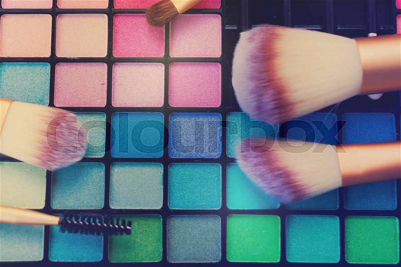Close up Make up Brushes and colorful eye-shadows palette, retro toned, stock photo