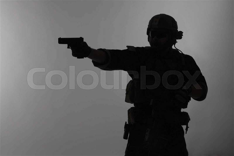 United states Marine Corps special operations command Marsoc raider with weapon aiming pistol. Silhouette of Marine Special Operator gray background, stock photo