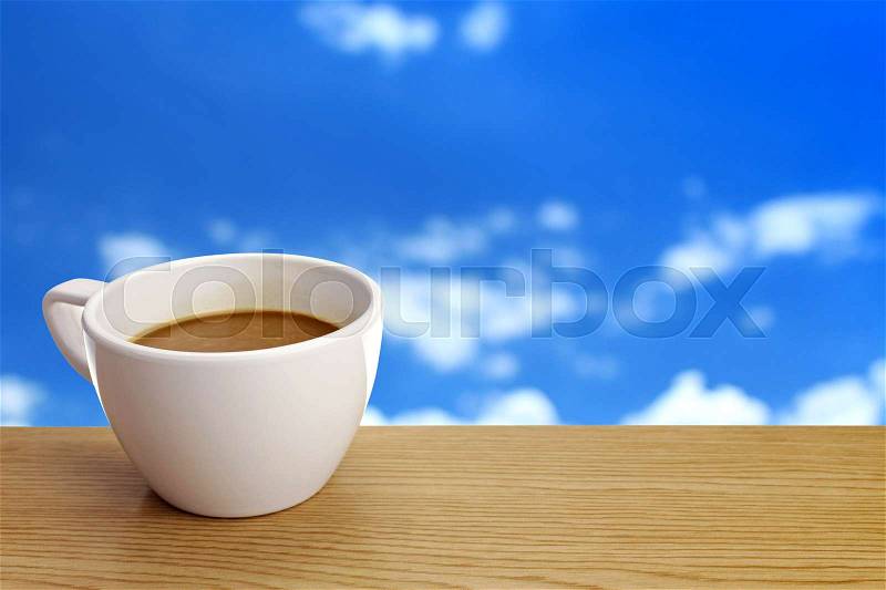 A cup of coffee on table over sky background, stock photo