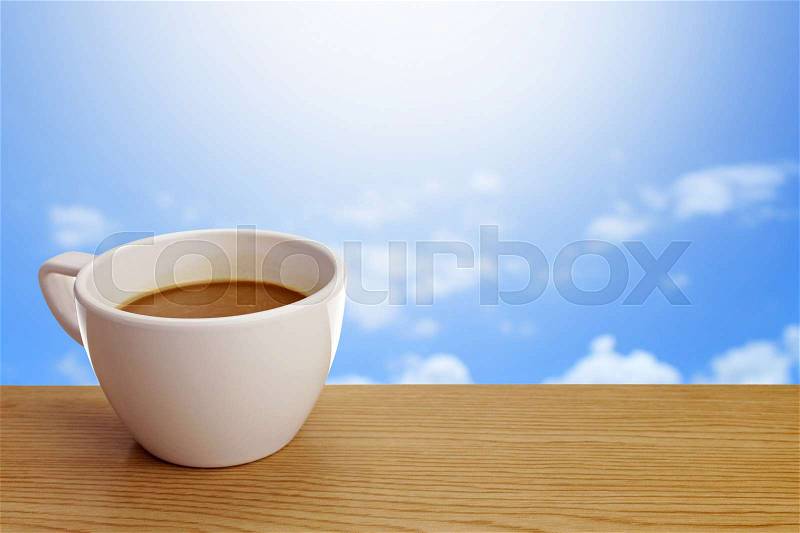 A cup of coffee on table over sky background, stock photo
