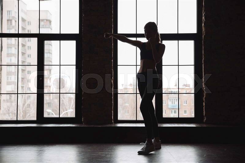 Silhouette of woman athlete standing and doing shadow boxing exercises, stock photo