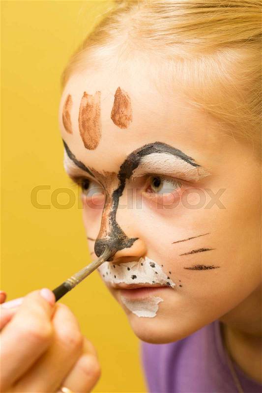 Mother painting a face of her daughter like girl cat , stock photo