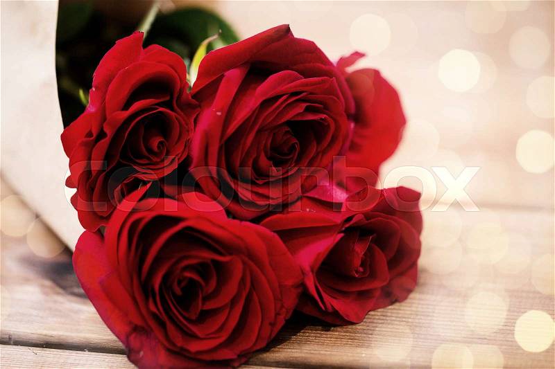 Love, date, flowers, valentines day and holidays concept - close up of red roses bunch wrapped into brown paper on wooden table (vintage effect), stock photo