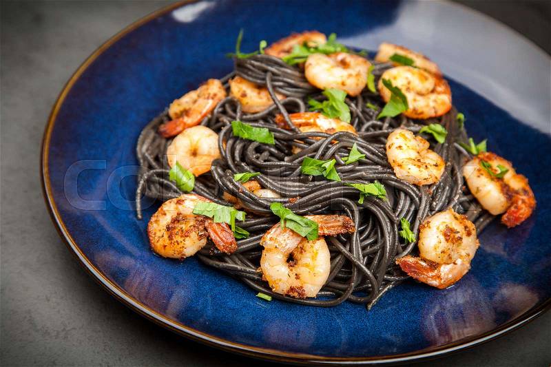 Black pasta with shrimps in garlic butter, stock photo