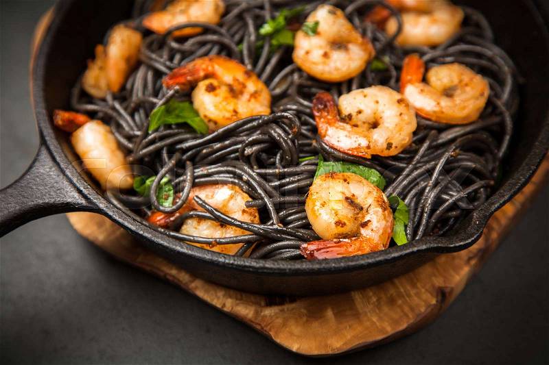 Black pasta with shrimps in garlic butter, stock photo