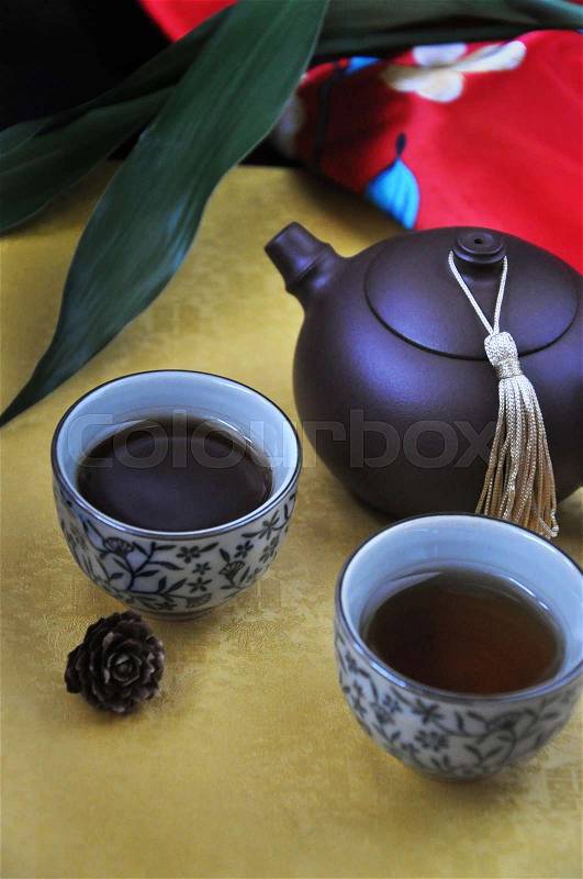 Black tea cup and pot put on golden background, stock photo