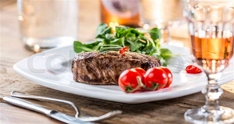 Beef Steak. Juicy beef steak. Gourmet steak with vegetables and glass of rose wine on wooden table, stock photo