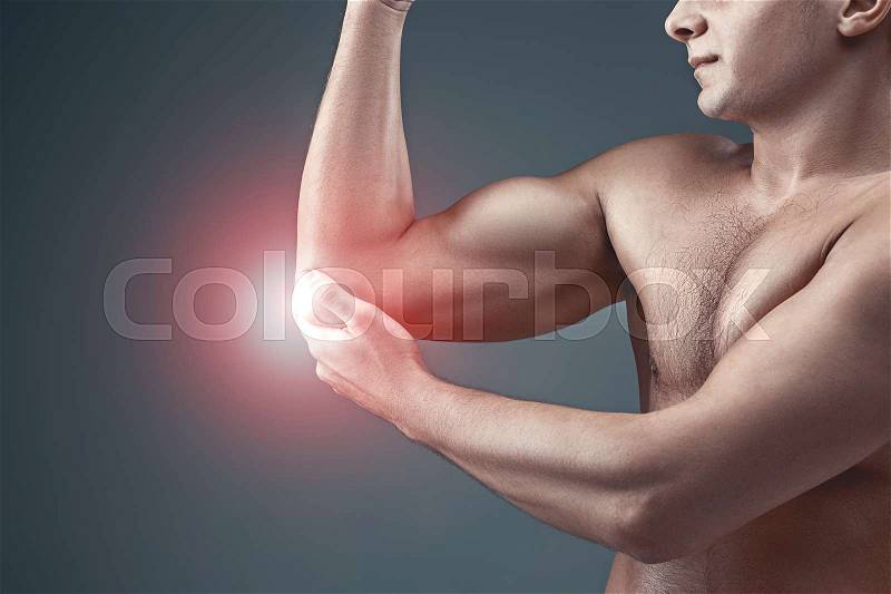 Man With Pain In Elbow. Pain relief concept on gray studio background, stock photo