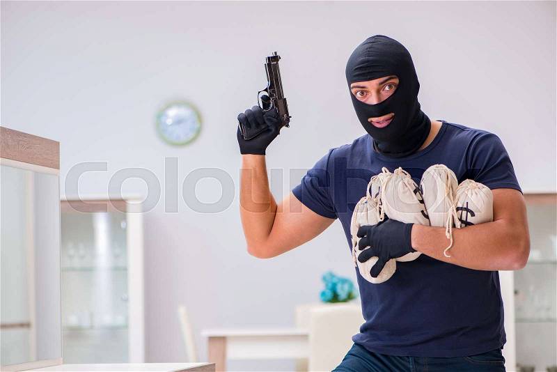 Robber wearing balaclava stealing valuable things, stock photo