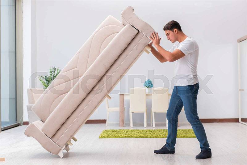 Man moving furniture at home, stock photo