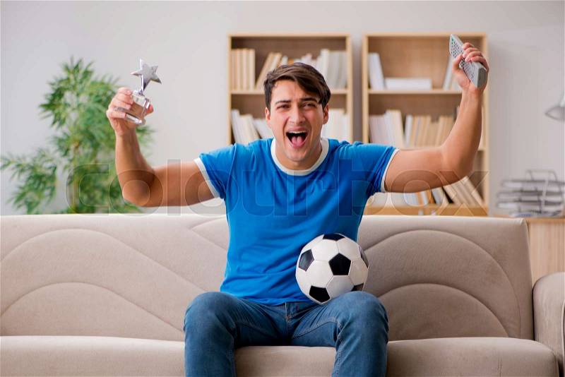Man watching football at home sitting in couch, stock photo
