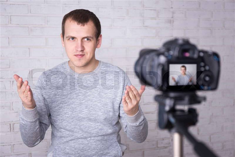 Video blogger making video over white brick wall, stock photo