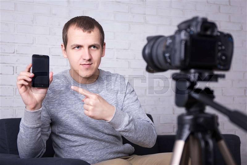 Young video blogger making new video about smart phones, stock photo