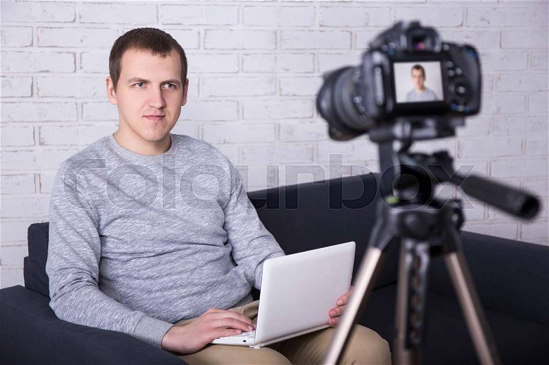 Young handsome man video blogger recording new video at home, stock photo