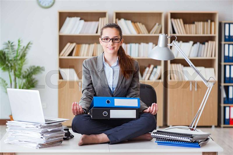 Busy angry businesswoman sitting on the desk in office, stock photo