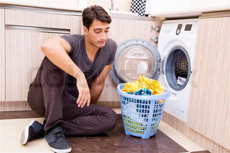 Young husband man doing laundry at home, stock photo