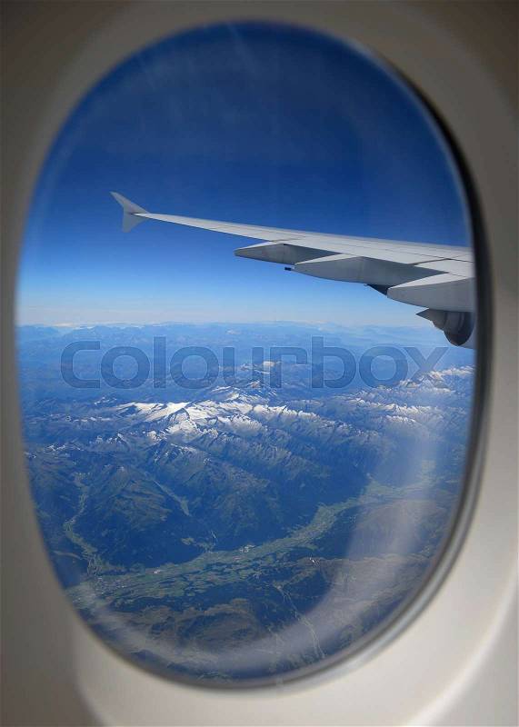 Looking through window, airplane wing and terrain with a nice blue sky, stock photo