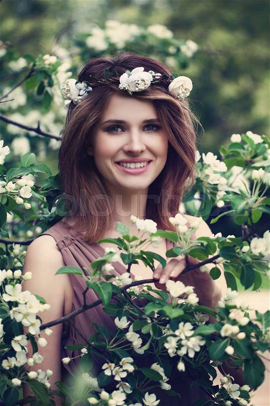 Happy Spring Model Girl Smiling. Beautiful Woman with Healthy Skin and Hair on Green Leaves and White Flowers, stock photo
