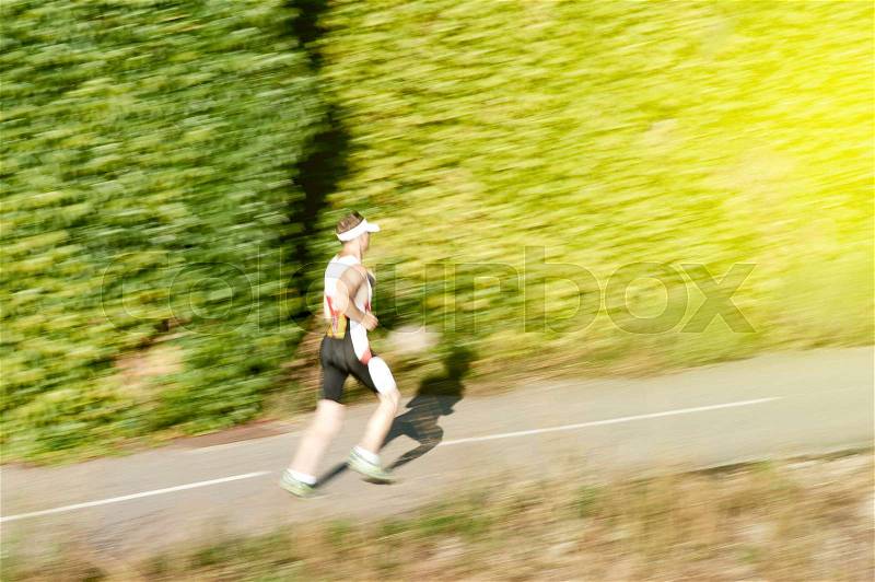 Silhouette of active man jogging in green environment - climbing hill toward success and aspirations of healthy lifestyle, stock photo