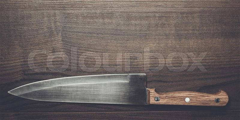 Kitchen knife on the brown wooden table background, stock photo