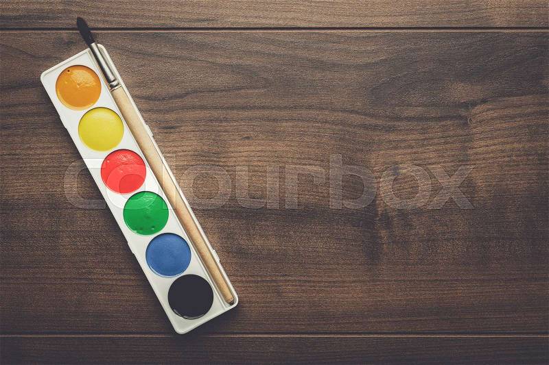 Box of paints and a brush on the wooden table, stock photo