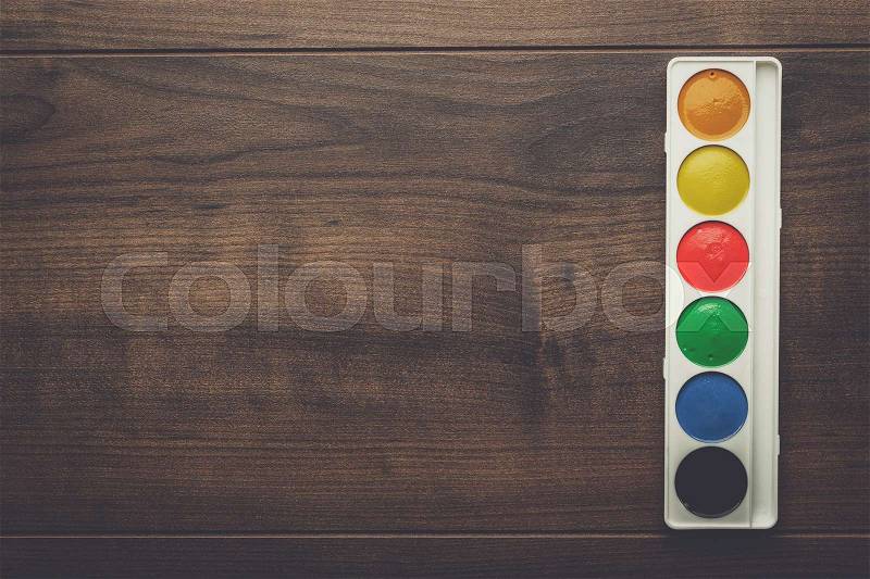Box of water paints on the wooden table, stock photo