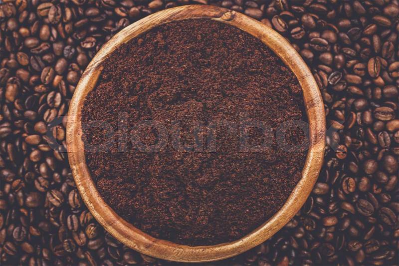 Coffee beans and wooden bowl full of ground coffee on the table background, stock photo